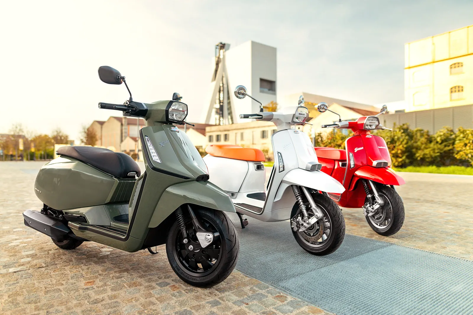 Lambretta X300 xanh rêu, G350 trắng và G350 đỏ xếp hàng trên quảng trường lát đá